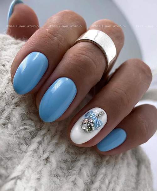 Manucure bleue avec un jouet de Noël